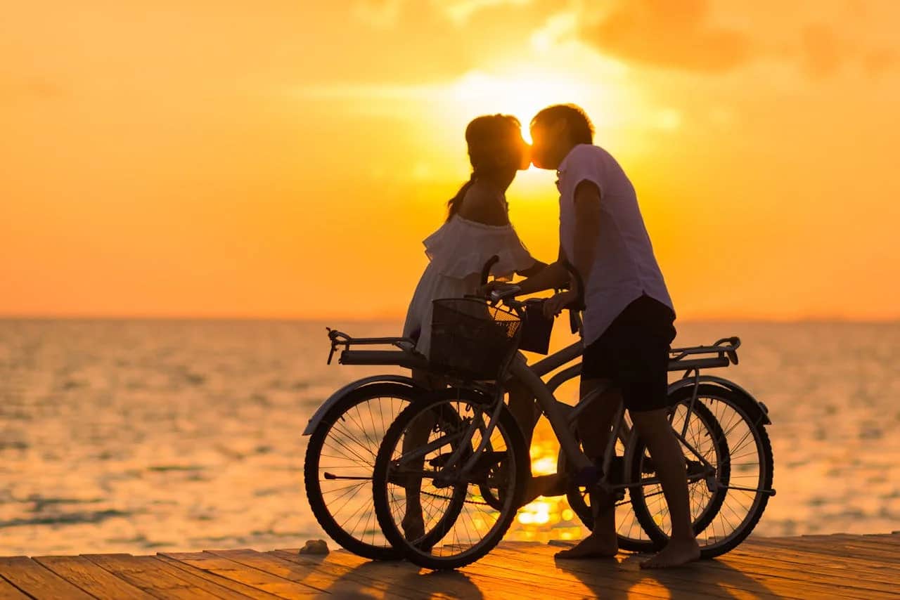 A couple with bicycles kissing in the sunset