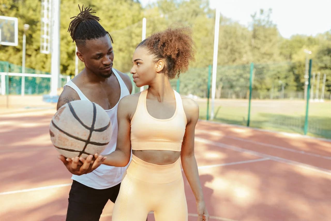 A couple sharing a basketball on an outdoor court